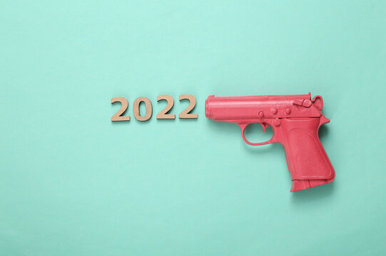 Pink pistol gun shooting 2022 on mint blue background. Creative new year layout. Flat lay. Top view