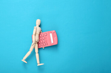 Wooden puppet with a calculator on a blue background. Economy concept