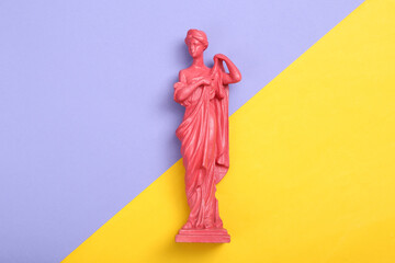 Creative layout. Pink Antique greek goddess statue on purple yellow background. Flat lay. Top view