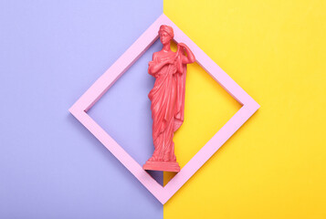 Creative layout. Pink Antique greek goddess statue in frame on purple yellow background. Minimalism. Flat lay. Top view