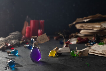 Bottles with colored contents are on the table. small bottles of potions and books of spells and recipes are on the wizard's desk in the smoke