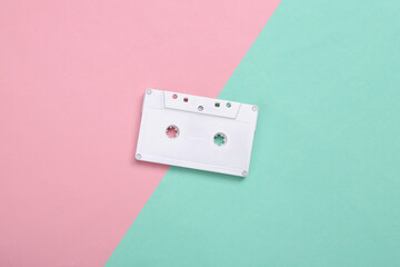 Creative music layout. White retro audio cassette on blue pink background. Pastel color trend. Minimalism. Concept art. Modern still life. Flat lay. Top view.