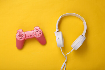 White headphones with gamepad on yellow background. Creative gaming layout. Top view. Flat lay