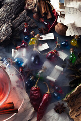 Bottles with colored contents are on the table. small bottles of potions and books of spells and recipes are on the wizard's desk in the smoke