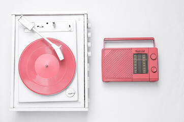 Musical layout. White vinyl record player and pink cool radio receiver on white background. Top view. Flat lay