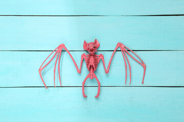 Pink bat skeleton on blue wooden background. Minimalism. Top view. Flat lay