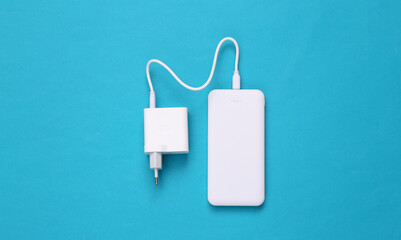 External portable battery (power bank) with charging device on a blue background. Top view. Flat lay