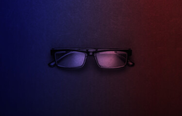 Classic eyeglasses in neon light. Top view.