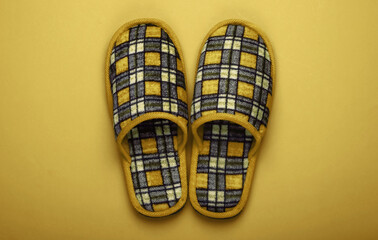 Checkered indoor slippers on yellow background. Top view