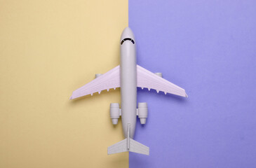 Toy model of plane on purple yellow pastel background. The concept of tourism, air travel, minimalism. Top view