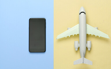 Online booking of air tickets via smartphone. Travel concept. Medel airplane, smartphone on yellow blue background. Top view. Minimalism