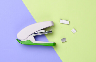 Stapler with paper clips on a blue-yellow pastel background. Minimalism. Top view