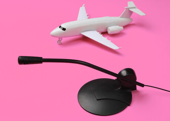 Air traffic controller, flight dispatcher. Plane figurine, microphone on pink background