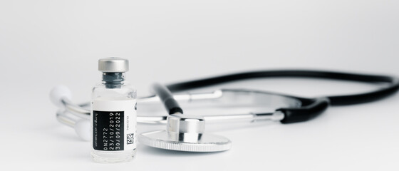 The vaccine vials, syringes and stethoscope are placed together on a white background. COVID-19 virus protection concept, vaccine invention and production concept.