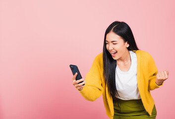 Happy Asian portrait beautiful cute young woman teen smiling excited   using mobile phone say yes!...