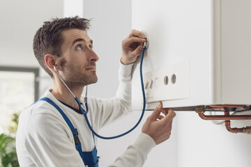 Expert plumber checking the boiler with a stethoscope