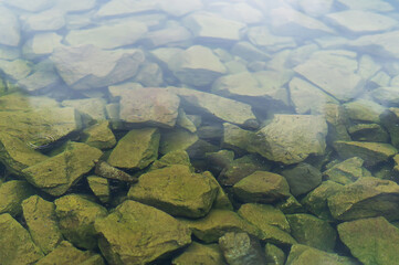 Old big Stones under clear water. Natural background of Stones at the bottom of a lake, river. A rock under the surface of the water. Wildlife concept, natural scenes