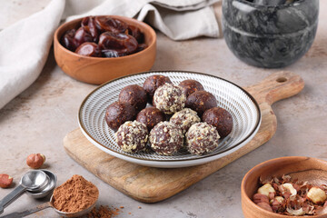 A plate with homemade raw chocolate energy balls, dates and hazelnut. Healthy vegan and vegetarian food. Horizontal view.