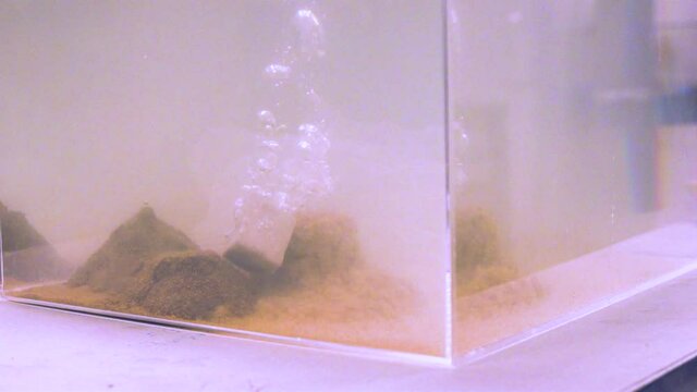 A slow motion shot of sand and earth bricks falling in water and degrading