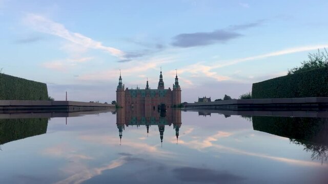 Frederiksborg Castle, in the Danish city of Hillerod, seen from one of the water fountains of its garden at dawn. Establishing/ long shot.