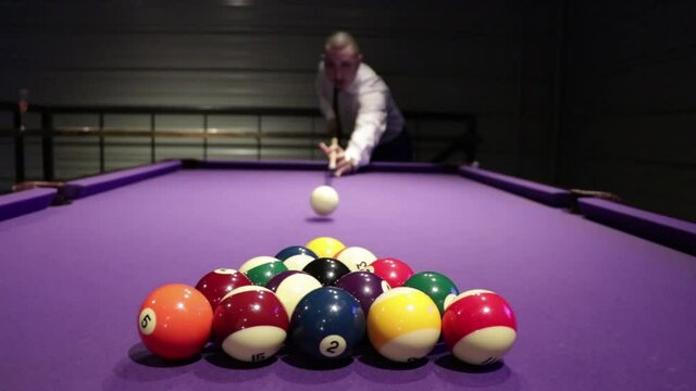 A guy breaking a pool table to start the game.