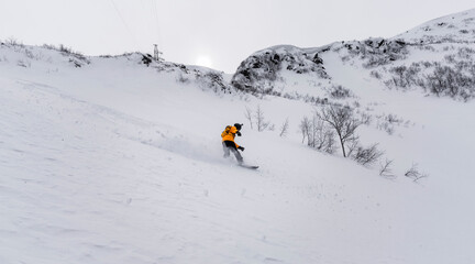 freeride on a snowboard in a bright suit rides a snowboard with large splashes of white snow