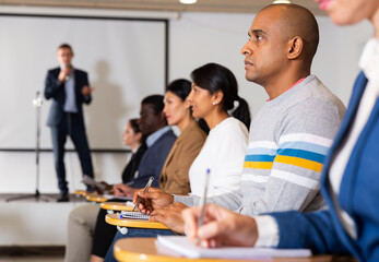 Portrait of confident man participant of business event listening to lecture at conference hall