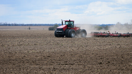 Obraz premium Red tractor with a plow on an agricultural field. work in the field with a big tractor. modern red tractor in the agricultural field. mechanism, Tractor plowing land. Harvester sowing wheat.