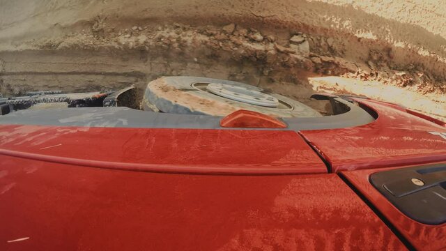 Industrial machinery. Truck driving on Muddy Terrain. Top view for a red truck wheel driving on mud and water. 4k footage