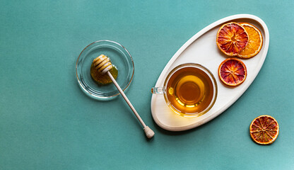 Cup of herbal tea with honey top view. Minimal summer still life, a cup of organic green tea on a colored background, with copy space.
