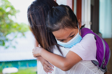 Asian child girl wearing medical mask for protection COVID-19 virus outbreak situation hugging her...