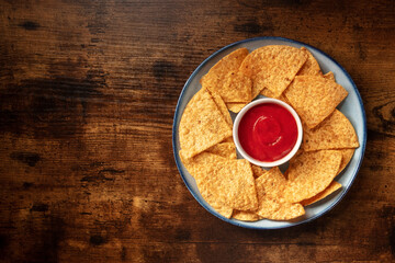 Nachos with tomato sauce, top shot on a rustic wooden table