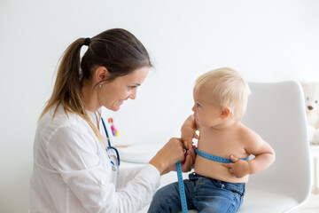 Pediatrician examining baby boy. Doctor using stethoscope to listen to kid