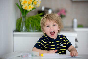 Blond toddler child, creating picture with application cuted paper animals, gift for mom