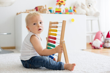 Cute little baby boy, playing with abacus at home