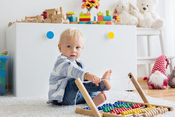 Cute little baby boy, playing with abacus at home