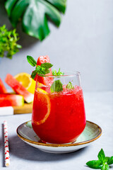 A glass of refreshing summer fresh watermelon with lemon and mint on light gray background, vertical photo
