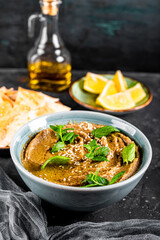  Traditional oriental appetizer baba ganoush with sesame seeds and mint leaves close-up. Eggplant hummus with pita crisps on the table, vertical photo