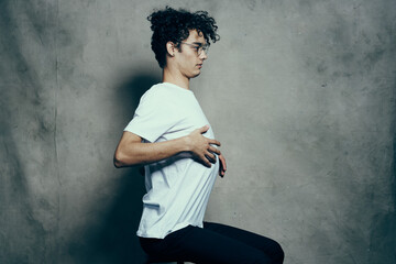 cute guy in a white t-shirt sits on a chair emotions curly hair