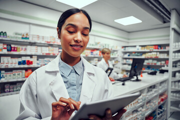 Fototapeta premium Portrait of woman wearing labcoat using digital tablet in drugstore