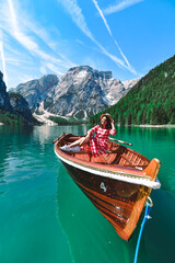 Fototapeta premium woman sitting in big brown boat at lago di braies lake in Italy