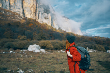 travel of a woman in a jacket with a backpack hat on his head blue sky and high mountains