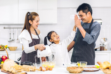 Portrait of enjoy happy love asian family father and mother with little asian girl daughter child having fun cooking food together with baking cookie and cake ingredient on table in kitchen