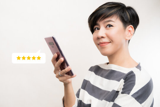 Customer experience ratings concept. An asian woman using a smartphone to submit stars feedback, and review to products or services she quite satisfied. Marketing business important tools. Surveys.