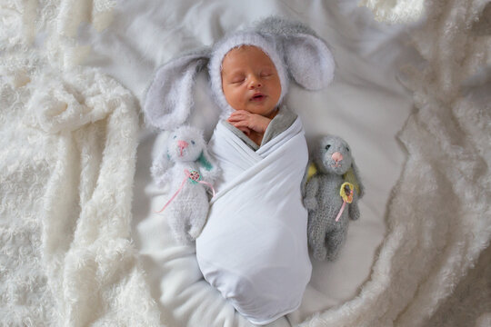 Newborn baby boy with soft toys hares. Newborn in a hat with ears