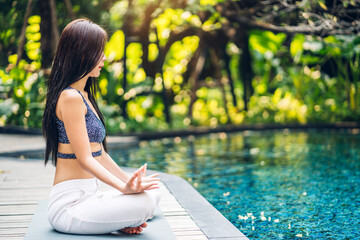 Portrait of sport asian woman in sportswear relax and practicing yoga do fitness exercise while sitting in swimming pool on summer travel vacation at resort spa.Diet concept.Fitness and healthy 