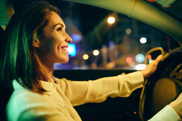 Beautiful happy woman enjoying while driving her car at night.