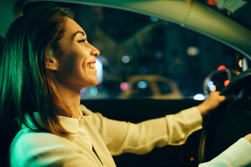 Young happy woman driving car and enjoying on road trip at night.