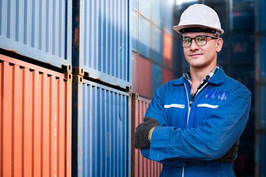 Portrait of manual man worker is standing with confident with blue working suite dress and safety helmet in front of warehouse container cargo. Concept of worker operating for shipping transport.