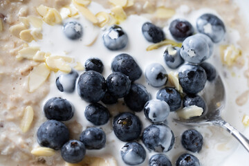 CLOSE UP ORGANIC BLUEBERRIES ON PORRIDGE WITH VEGAN OAT CREAM FLAKED ALMONDS SPOON JUST SEEN 
